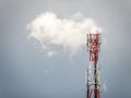 Red and white tall cellular repeater with blue sky and white cotton cloud in the background