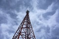 Cellular telecommunications tower for communication. High cell tower against the sky with clouds Royalty Free Stock Photo