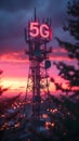 Cellular tower with glowing red 5G sign at sunset.