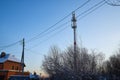 Cellular tower in village on winter sunny day or evening and blue sky background Royalty Free Stock Photo