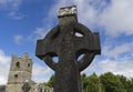 Celtic cross in the foreground with the ruins of a church tower Royalty Free Stock Photo