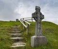 Celtic cross on the slope of a green hill.