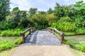 Cement bridge with wooden balustrade over pond to garden Royalty Free Stock Photo