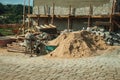 Cement mixer with wooden scaffolding and sand pile