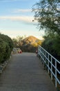 Cement path walkway for pedestrians with white metal handrail and background sunny mountain in early morning sunrise