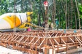 The cement truck is pouring concrete to a wooden mold of house foundation.