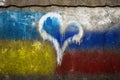 Cement wall with graphite of the Ukraine and Russian flag. Heart in the middle.