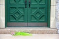Cemetery crypt with flower bouquet in front of heavy green doors