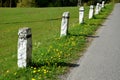 Granite stone bollards old line the mountain road at the moat on the edge of the white curb with a black stripe in a row escort