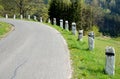 Granite stone bollards old line the mountain road at the moat on the edge of the white curb with a black stripe in a row turn