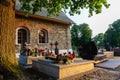 Cemetery in Milowka, Poland with traditional granite graves decorated with colorful artificial flowers.