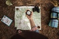 A girl is holding a compass to orientate in the forest with a map.