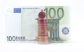 1 cent coin standing on top of stack of euro coins near 100 euro bank note. Royalty Free Stock Photo