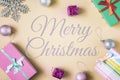 In the center of a beige background, the inscription is Merry Christmas. Spread around the boxes with gifts and