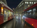 The center of Bern at night with buses, trams, statues and cathedrals with locals and tourists walking by