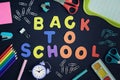 In the center of a black background with colored letters lined inscription Back to School. Around are stationery and Royalty Free Stock Photo