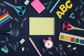 In the center of the black background, a notepad with a place for text lies in a puke. Bright colored school and office Royalty Free Stock Photo