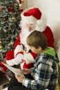 Santa Claus and a boy looking at paper Royalty Free Stock Photo