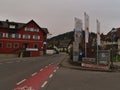 Center of small village SchÃÂ¶nau, part of Lindau, with main road, bicycle lane, hotel, advertising flags and residential building.