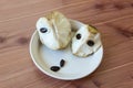 Centered close view of two chunks of cherimoya fruit Annona cherimola on a shallow dish with numerous black seeds