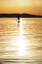 Centered sun reflection in water and silhouette of young woman paddling at sunset on a stand up paddleboard SUP in Croatia. Royalty Free Stock Photo