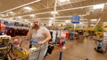 Customer pushing a cart while talking on a cellphone wearing a face