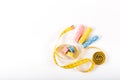 A centimeter tape and two spools of yellow, blue and pink thread on a white background in a minimalistic style with a place for Royalty Free Stock Photo