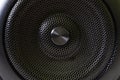 The central fragment of a modern audio speaker with a protective black metal grille. Macro Royalty Free Stock Photo