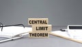 CENTRAL LIMIT THEOREM text on wooden block with notebook,chart and calculator, grey background