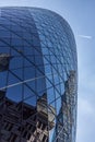 CENTRAL LONDON / ENGLAND - 18.05.2014 - Sky-scraper reflections are seen in the Gherkin's windows while a plane flies over Royalty Free Stock Photo