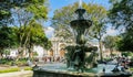 View of Central Park with a beautiful, ornate water fountain and Saint James Cathedral in the background. Antigua, Guatemala