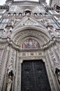 Central part of the facade of the Cathedral of Santa Maria del Fiore, with the large dark door, the large fresco and the rose wind