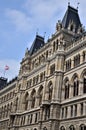 Central part of the facade of a large, historic building in Vienna, in the blue sky veiled with light clouds, a flag is waving. Royalty Free Stock Photo