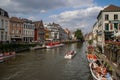 The central part of the house with a canal, bridge, medieval buildings and people walking