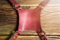 Central part pink camera harness, multi-camera strap harness, leather camera strap on brown wooden background. Glare.