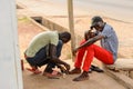 Unidentified Ghanaian man treats his friend's wound in local vi