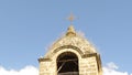 A century-old orthodox church belfry dome covered with grass. Cross, blue sky and white clouds. Christian Orthodox Religion.