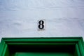 Ceramic black number 8 white wall over green door