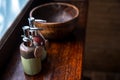 Ceramic bottles of shampoo and shower gel are placed in a large wooden bowl.