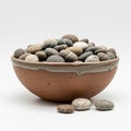 A ceramic bowl filled with smooth, multicolored pebbles sits on a flat surface. The Royalty Free Stock Photo