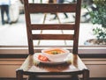 Ceramic bowl filled with a steaming vegetable soup on a wooden chair