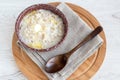 In a ceramic bowl, freshly brewed nutritious delicious oatmeal with butter for breakfast with a wooden spoon.