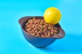 Ceramic bowl full of dry food for pet and tennis ball on blue background Royalty Free Stock Photo