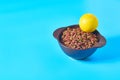 Ceramic bowl full of dry food for pet and rubber tennis ball on blue background Royalty Free Stock Photo