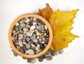 Ceramic bowl with pebbles and autumn leaf Royalty Free Stock Photo