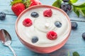 Ceramic bowl with plain yoghurt and berries on the table. Light summer mood