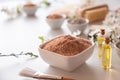 Ceramic bowl with red clay powder, ingredients for homemade facial and body mask or scrub and fresh sprig of flowering cherry