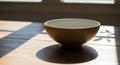 A ceramic bowl sits on a wooden table, with sunlight streaming through a window, casting distinct Royalty Free Stock Photo