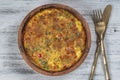 Ceramic bowl with vegetable frittata, simple vegetarian food. Frittata with tomato, pepper, onion and cheese on wooden table,