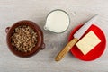 Ceramic pot with buckwheat porridge, jug with milk, knife, piece of butter in saucer on wooden table. Top view Royalty Free Stock Photo